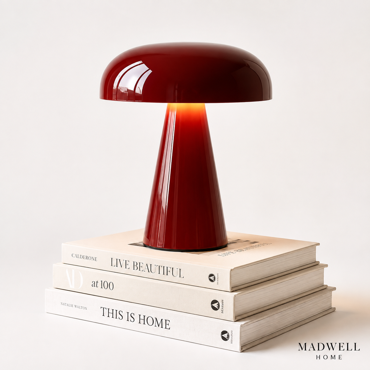 Red mushroom portable table lamp in burgundy on a stack of books, white background