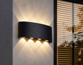 Matte black LED wall sconce mounted outdoors casting warm up and down light