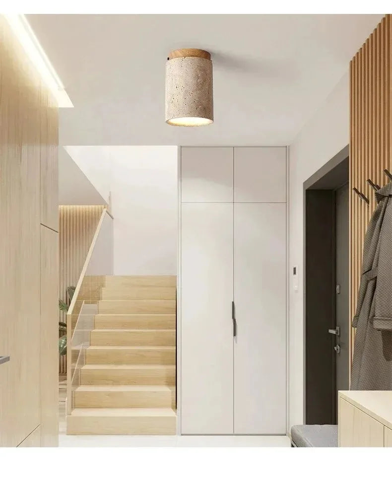 Single travertine stone and wood flush mount ceiling light above a staircase entryway in a bright Scandinavian interior