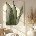 Minimalist green leaf botanical line art print in white frame hanging in a bright Scandinavian living room