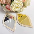 Leaf-shaped decorative mirrors with natural wood frames in silver and gold finishes, displayed with pink and white roses