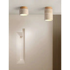 Two travertine stone and wood flush mount ceiling lights in a neutral modern hallway with slatted wood wall panel