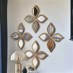 Multiple leaf-shaped wood frame mirrors arranged in a floral diamond pattern on a living room wall