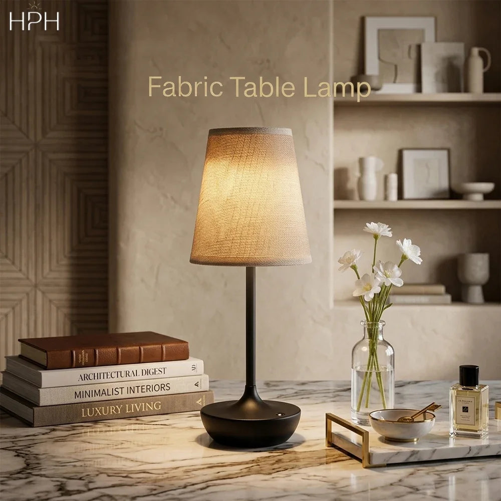 Wireless LED fabric table lamp in black finish styled on a marble surface with books and flowers in a luxury interior