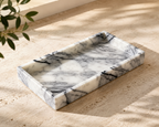 Marble tray on sandy surface with natural light and olive branch