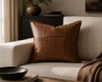 Woven leather throw pillow styled on a cream sofa in a warm modern living room